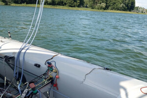 Zdjęcie przedstawia fragment uszkodzonej łodzi oraz jezioro.