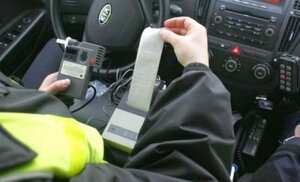 Zdjęcie przedstawia fragment policjanta siedzącego w radiowozie.