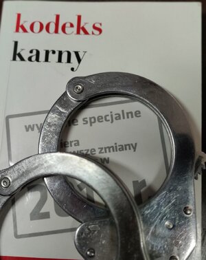 Zdjęcie przedstawia kodeks karny oraz kajdanki.
