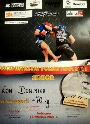 Zdjęcie przedstawia plakat na którym widać dwóch walczących w zawodach MMA zawodników. Na plakacie widnieje napis VICEMISTRZYNI POLSKI MMA 2021 SENIOR - KON DOMINIKA w kategorii + 70kg.