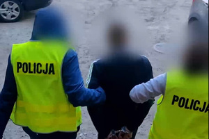 Zdjęcie przedstawia nieumundurowanych policjantów prowadzących zatrzymanego mężczyznę.
