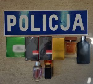 Zdjęcie przedstawia zabezpieczone perfumy a obok napis &quot;Policja&quot;.