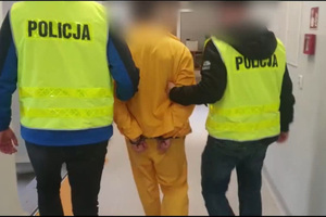 Zdjęcie przedstawia nieumundurowanych policjantów prowadzących zatrzymanego mężczyznę.