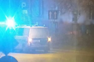 Policyjny radiowóz w porze nocnej z włączonymi sygnałami świetlnymi.