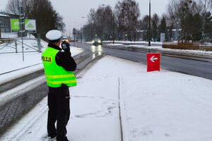 Zdjęcie przedstawia umundurowanego policjanta prowadzącego kontrolę prędkości.