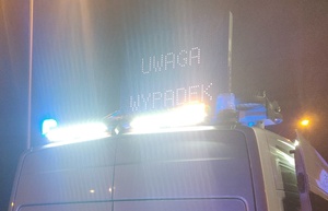 Zdjęcie przedstawia fragment radiowozu a napisem "Uwaga wypadek".