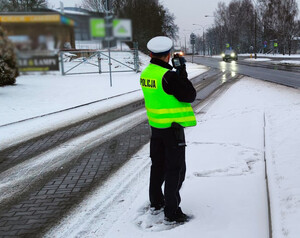 Zdjęcie przedstawia policjanta mierzącego prędkość.