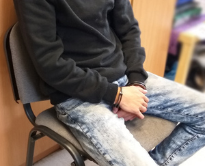 Zdjęcie przedstawia zatrzymanego mężczyznę siedzącego na krześle.