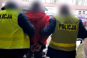 Zdjęcie przedstawia policjantów prowadzących zatrzymanego mężczyznę.