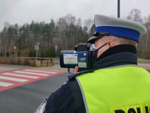 Zdjęcie przedstawia policjanta mierzącego prędkość.