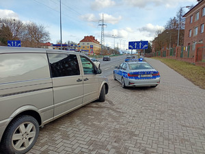 Zdjęcie przedstawia auto podczas kontroli drogowej a obok policyjny radiowóz.