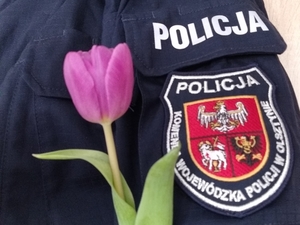 Zdjęcie przedstawia fragment policjanta z kwiatkiem.