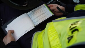 Zdjęcie przedstawia fragment policjanta z mandatownikiem.