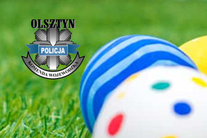 Logotyp policji warmińsko-mazurskiej oraz pisanki na tle trawy