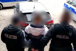 Zdjęcie przedstawia nieumundurowanych policjantów prowadzących zatrzymanego mężczyznę.
