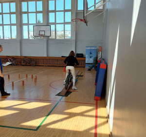 Zdjęcie przedstawia organizatorów oraz uczestników w wieku szkolnym konkursu BRD organizowanego na terenie SP w Barczewie. Zdjęcie wykonano w szkolnej sali sportowej.