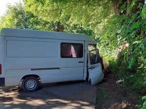 Zdjęcie przedstawia biały bus uczestniczący w zdarzeniu drogowym.