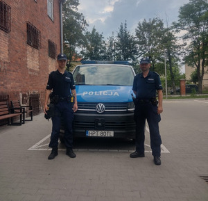 Zdjęcie przedstawia umundurowanych policjantów na tle radiowozu.