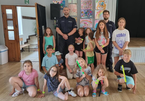 Zdjęcie przedstawia dzieci podczas spotkania profilaktycznego oraz dwóch policjantów dzielnicowych.