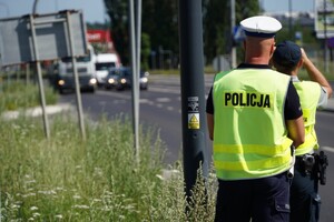 Zdjęcie przedstawia umundurowanych policjantów a w tle ruch uliczny.