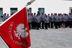 Sztandar z godłem Polski i policjanci w tle