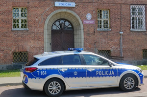 Zdjęcie przedstawia radiowóz a w tle budynek Komisariatu Policji w Dobrym Mieście.