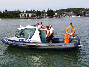 Zdjęcie przedstawia policyjną łódź wraz z funkcjonariuszami na jeziorze.