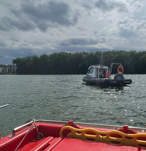 Zdjęcie przedstawia policyjną łódź wraz z funkcjonariuszami na jeziorze.