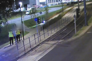 Zdjęcie przestawia przedstawia policjantów zatrzymujących do kontroli drogowej dwóch mężczyzn jadących hulajnogą elektryczną.