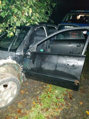 Zdjęcie przedstawia osobowy samochód koloru czarnego z uszkodzeniami pokolizyjnymi.