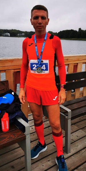asp. Robert Rachubka - policjant, który brał udział w półmaratonie. Zdjęcie wykonano w trakcie biegu policjanta ubranego w strój koloru pomarańczowego.