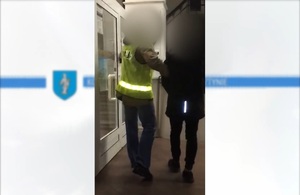 Zdjęcie przedstawia prowadzenie zatrzymanego mężczyzny.