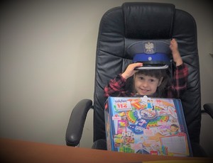 Zdjęcie przedstawia 3-letnią dziewczynkę siedzącą na fotelu Komendanta Komisariatu Policji w Biskupcu