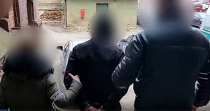 Zdjęcie przedstawia prowadzenie zatrzymanego mężczyznę.