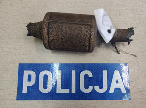 Zdjęcie przedstawia zabezpieczony katalizator oraz powyżej napis &quot;Policja&quot;.
