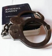 Zdjęcie przedstawia kodeks karny oraz policyjne kajdanki.