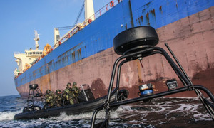 Łódka z policyjnymi kontrterrorystami podpływa do burty dużego statku towarowego
