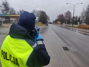 Zdjęcie przedstawia fragment policjantki mierzącej prędkość.