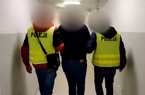 Zdjęcie przedstawia prowadzenie zatrzymanego mężczyznę.