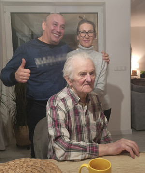 Robert Treszczyński i Anna Pyrzyna zaopiekowali się 93- letnim mężczyzną, zdjęcie przedstawia mężczyznę i kobietę w mieszkaniu, wraz z 93- latkiem.