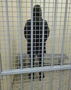 Zdjęcie przedstawia zatrzymanego za kratami.