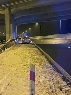 Zdjęcie przedstawia zimową drogę i słupek drogowy.