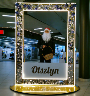 Zdjęcie przedstawia policjanta w czerwonej czapce, na tle ramki z napisem Olsztyn.