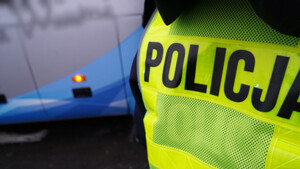 Zdjęcie przedstawia napis policja, a w tle autobus.