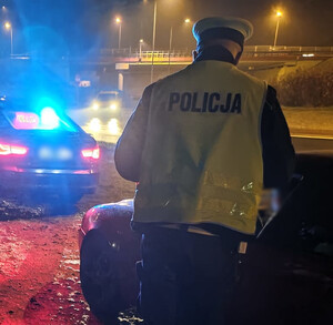 Zdjęcie przedstawia policjanta podczas kontroli drogowej.