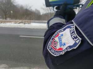 Zdjęcie przedstawia fragment policjanta mierzącego prędkość.