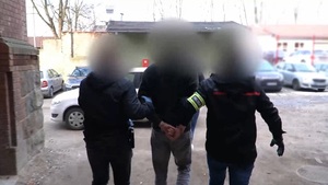 Zdjęcie przedstawia prowadzenie zatrzymanego mężczyzny.