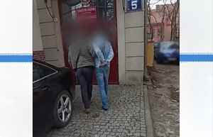 Zdjęcie przedstawia prowadzenie zatrzymanego mężczyzny.