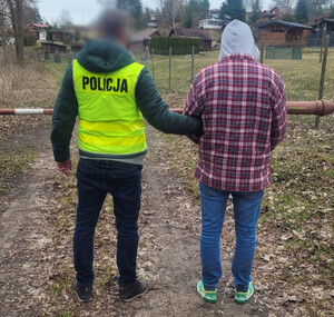 Zdjęcie przedstawia zatrzymanego mężczyznę oraz policjanta.