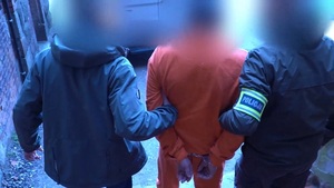 Zdjęcie przedstawia prowadzenie zatrzymanego mężczyzny.